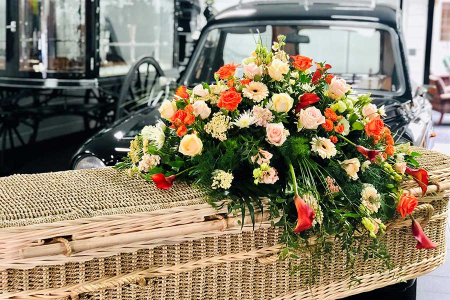 Wicker coffin with sunning floral tribute on top